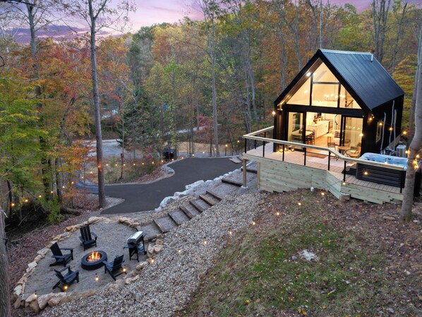 A cabin with a deck, outdoor seating, and a fire pit.