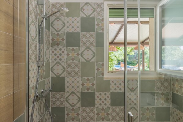 A bathroom with patterned tiles, a shower, and a window with a view of greenery. - Tina's House with Pool - 2 Bedrooms - 7 km from the Torre Guaceto Nature Reserve (San Vito Dei Normanni)