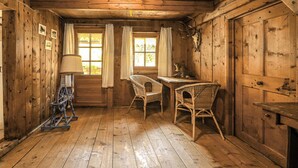 A rustic wooden room with two wicker chairs, a small table, and a window with curtains. - Beautiful home in Sankt Sigmund with sauna (Sankt Sigmund)