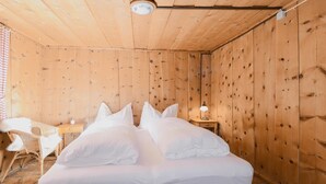 A wooden room with a bed, a small table, and a chair. - Beautiful home in Sankt Sigmund with sauna (Sankt Sigmund)