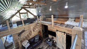 Un dormitorio estilo loft con techo de madera, una cama litera, un sofá y una mesita.