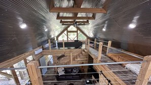 Una cabaña rústica con interior de madera, un altillo y un espacio exterior cercado.