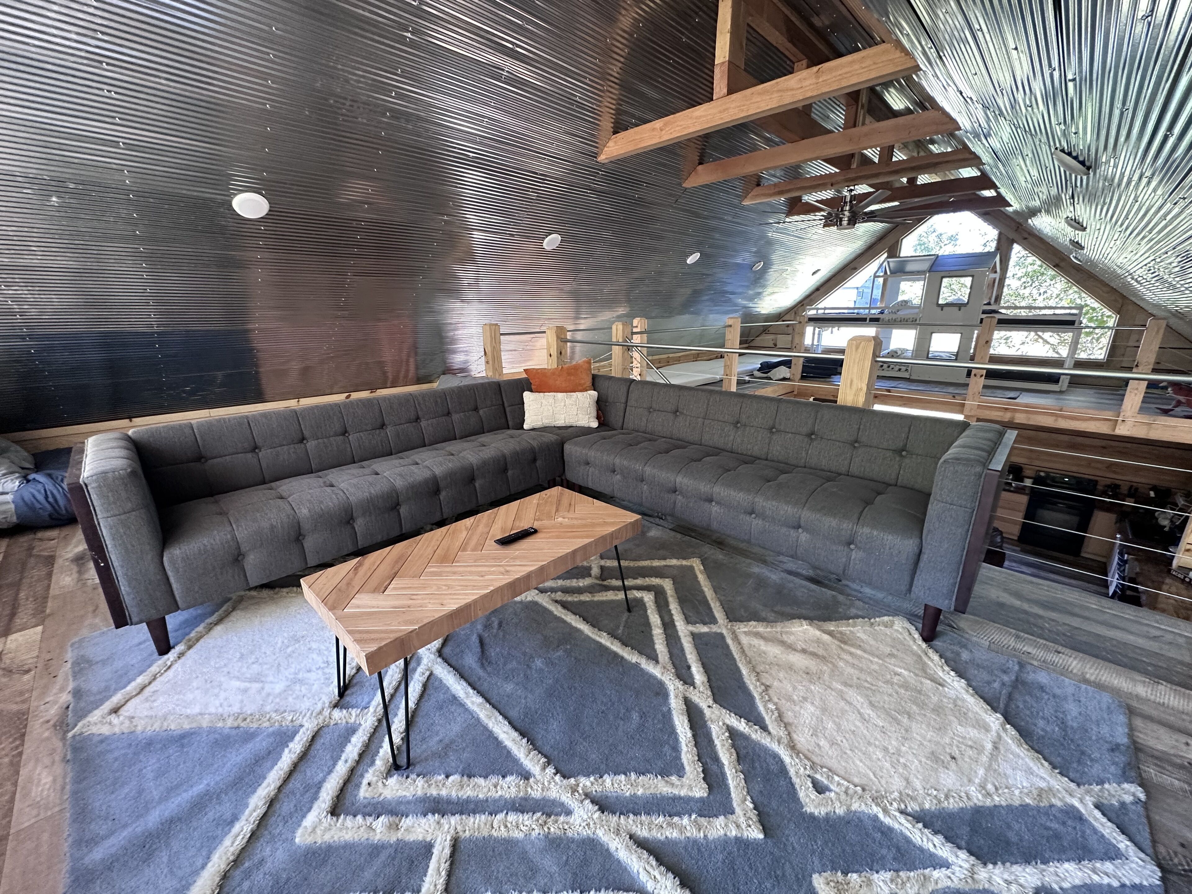 Una sala de estar moderna con un sofá modular, una mesa de centro de madera y alfombras estampadas.