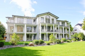 A large, multi-story building with balconies and large windows, surrounded by well-maintained lawns and trees. - Moderne Ferienwohnung mit Eigener Sauna und Balkon - Villa Pauline Fewo 06 - Villa Pauline (Göhren)