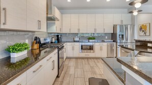 Una cocina moderna con armarios blancos, electrodomésticos de acero inoxidable y una encimera de granito.