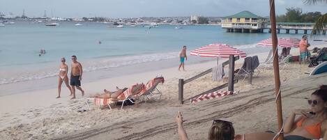 A beach with umbrellas, lounge chairs, and a view of the sea.