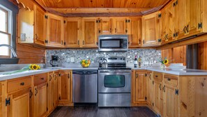 Une cuisine avec des armoires en bois, des appareils électroménagers en acier inoxydable et un dosseret carrelé.