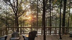 Eine Holzterrasse mit Feuerstelle, zwei Stühlen und einem Tisch.