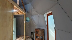 Ein geräumiges Zelt mit Holzboden, einem kleinen Schrank und einem Fenster.