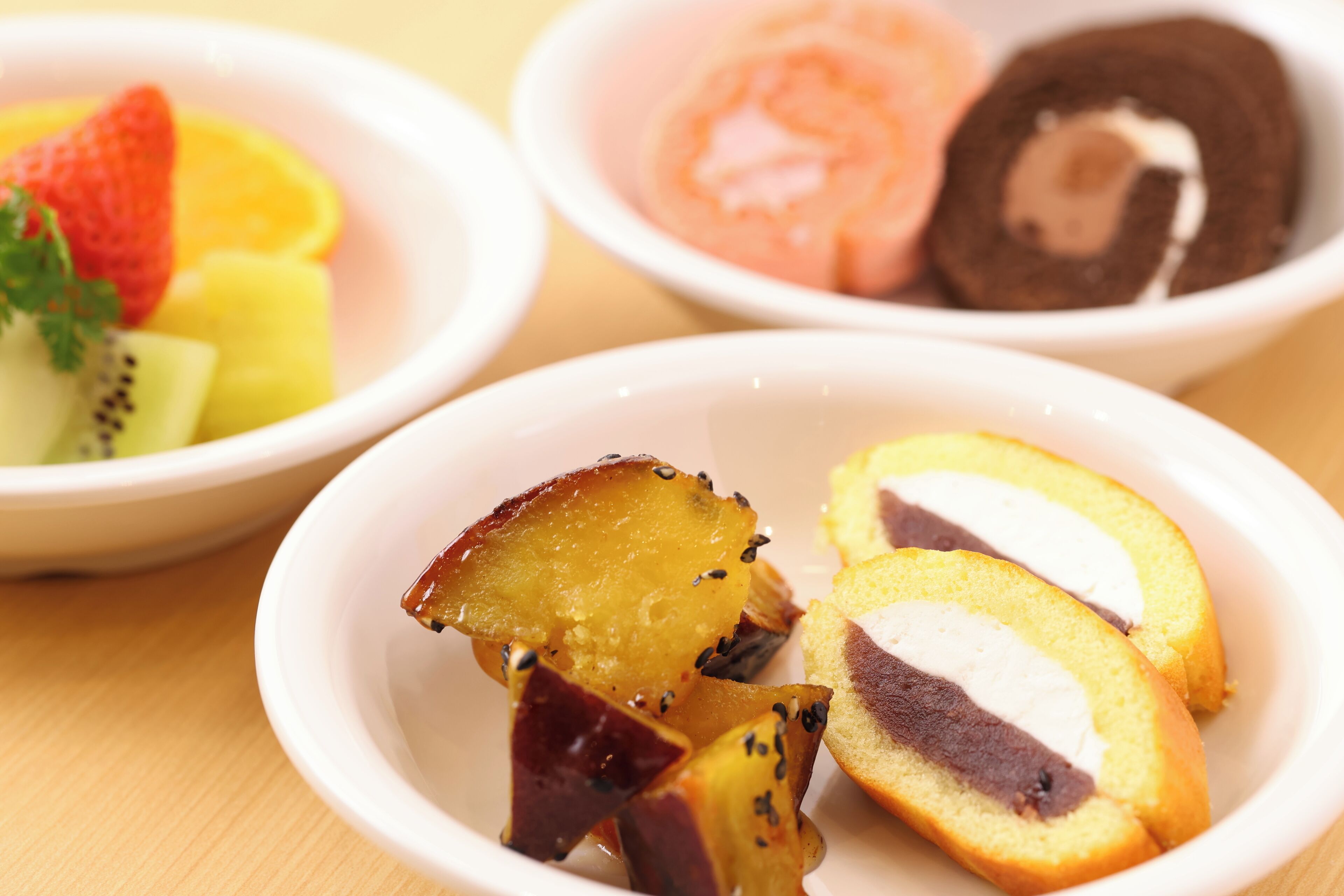 A variety of desserts in bowls, including slices of cake and fruit.