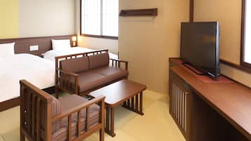 Habitación de hotel con dos camas, un sofá, un televisor y una mesita.
