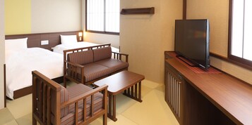 Habitación de hotel con dos camas, un sofá, un televisor y una mesita.