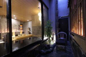 A spa area with a wooden ceiling, a reception desk, and a seating area with a chair and plants.