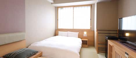 A hotel room with a bed, bedside table, TV, and a window.