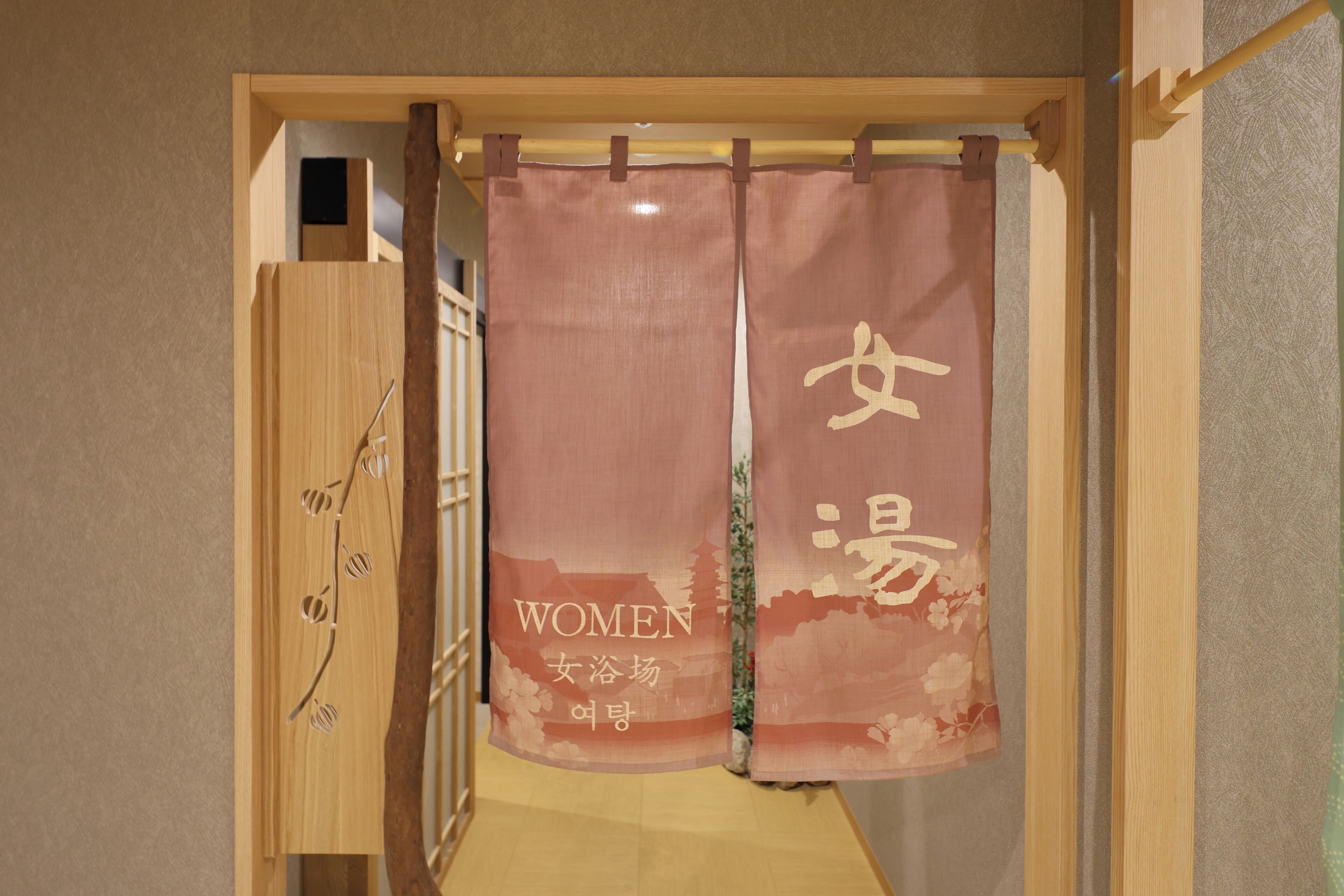 A room with a wooden wardrobe, a bed with a wooden headboard, and a curtain with text.