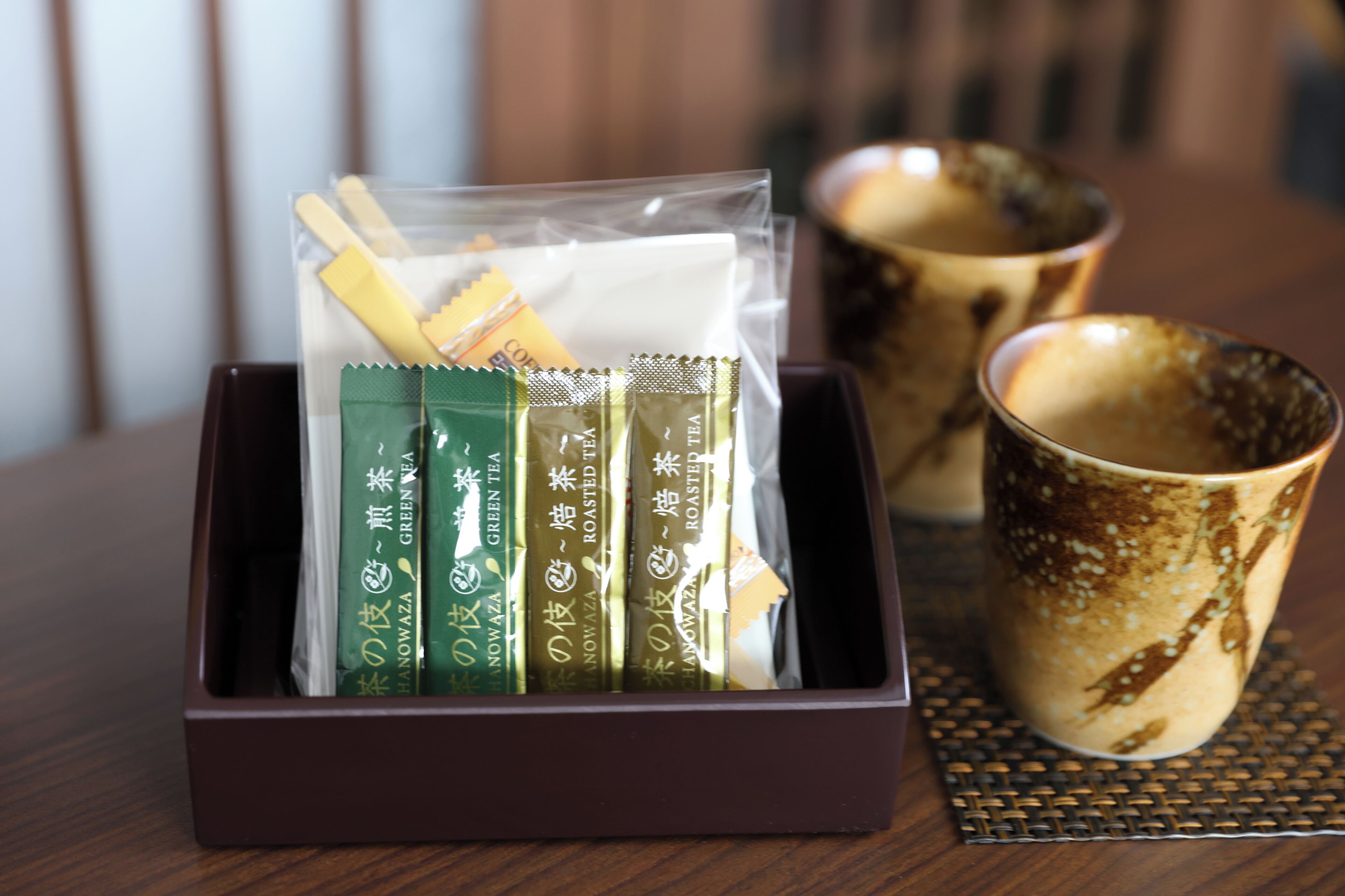 A box containing tea packets and a ceramic mug on a table.