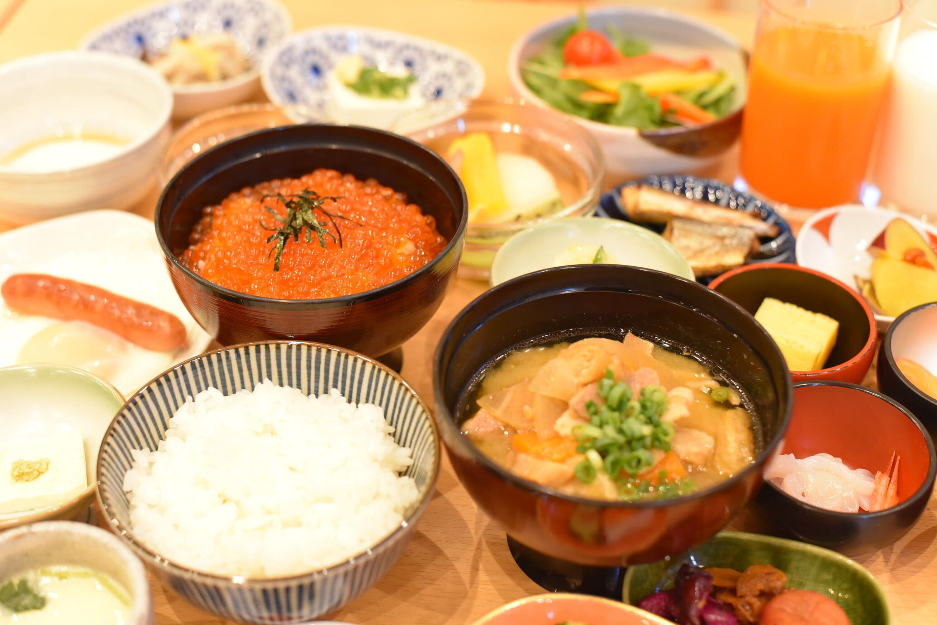 A variety of dishes including a bowl of red caviar, a bowl of soup with vegetables, and several small bowls of different foods.