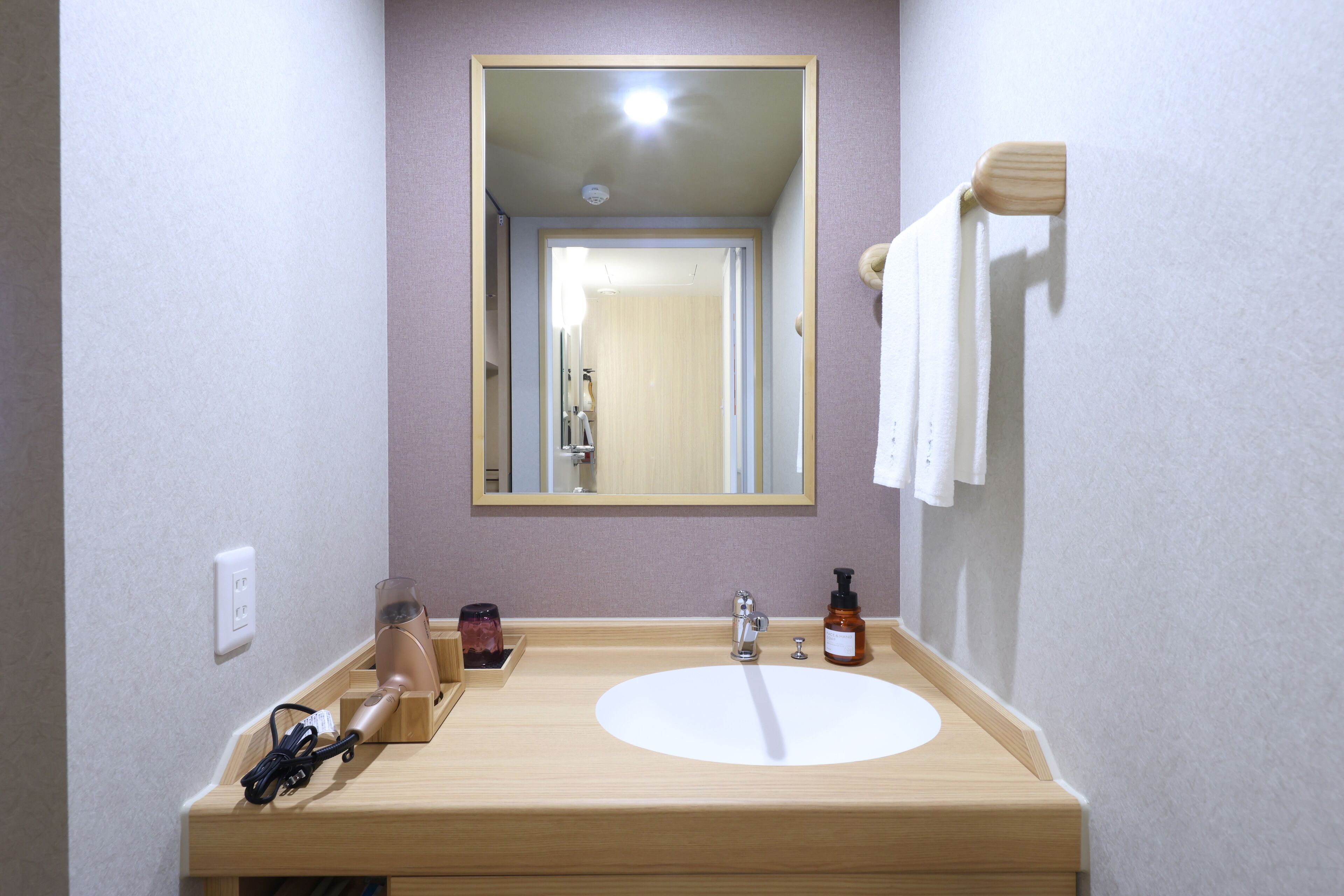 A bathroom with a wooden vanity, a mirror, a sink, and a towel rack.