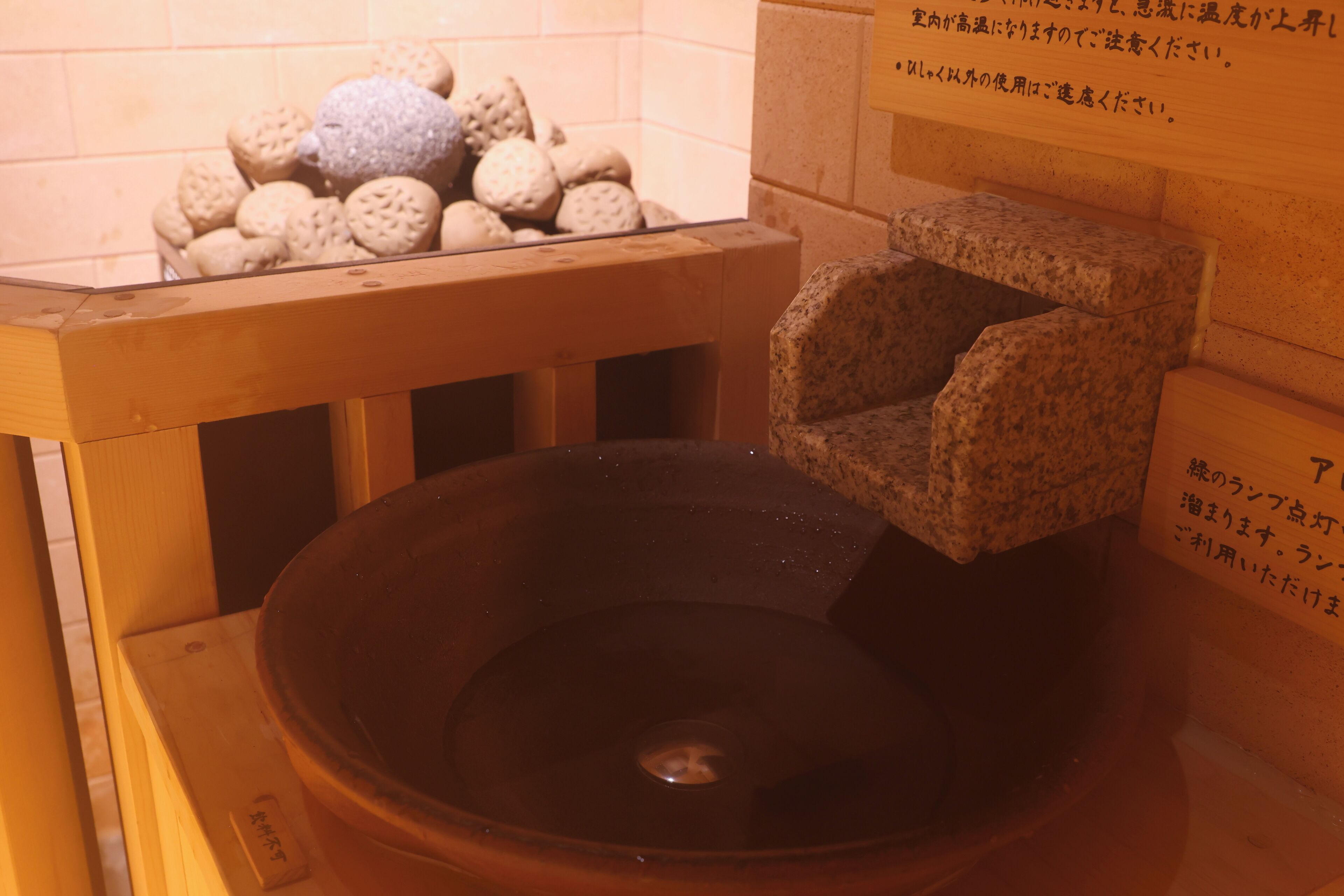 A stone basin with a wooden platform and a pile of round, textured stones.
