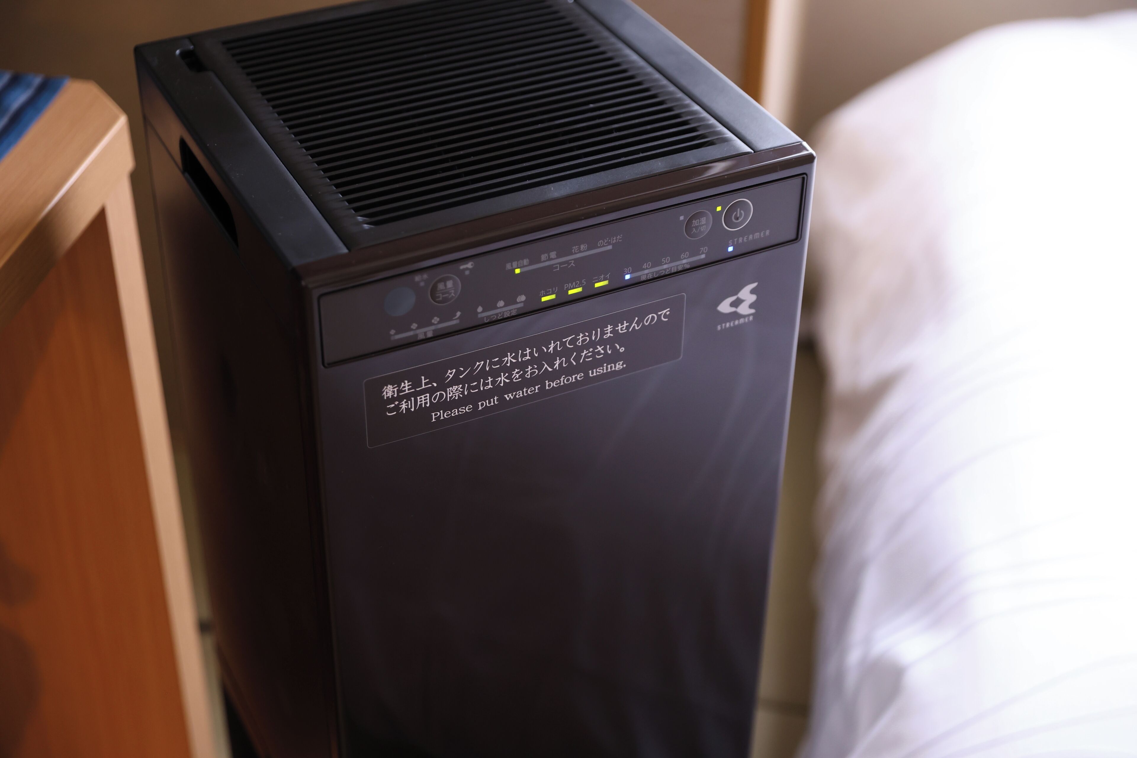 A black portable heater with a control panel and a warning label in a hotel room.