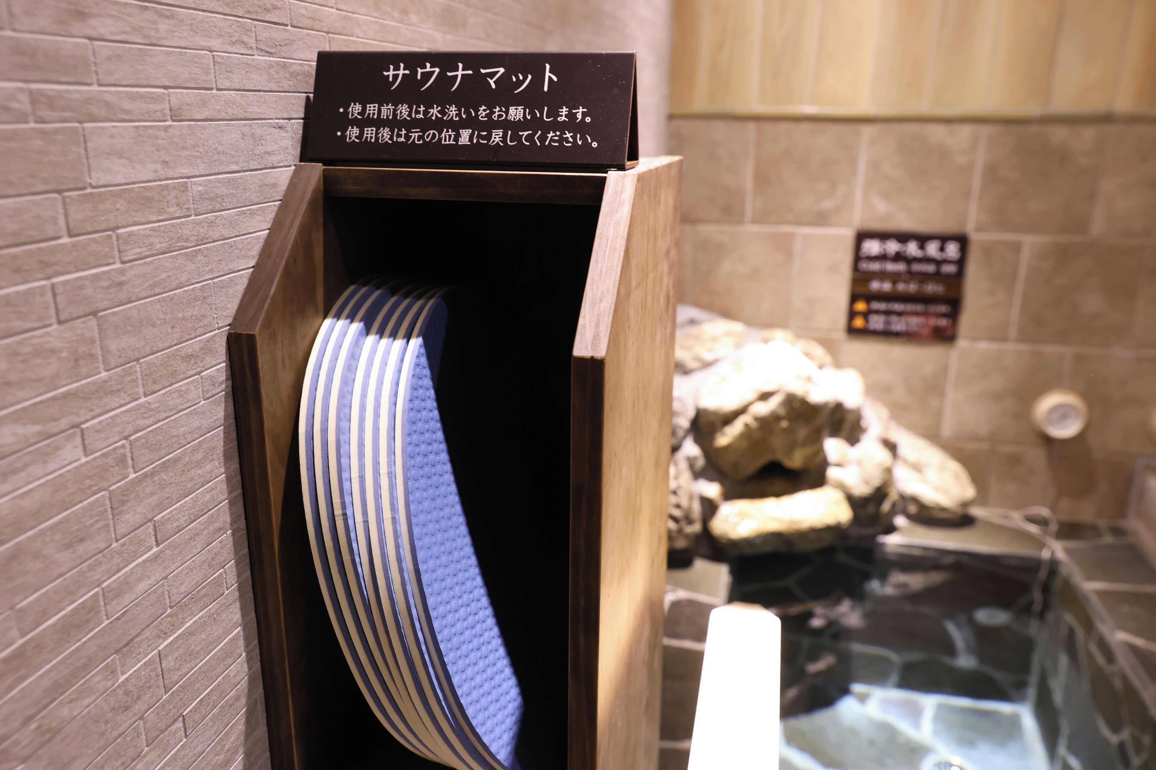 Een houten doos met een Japanse bord, een gestreept voorwerp binnenin, en een stenen muur op de achtergrond.