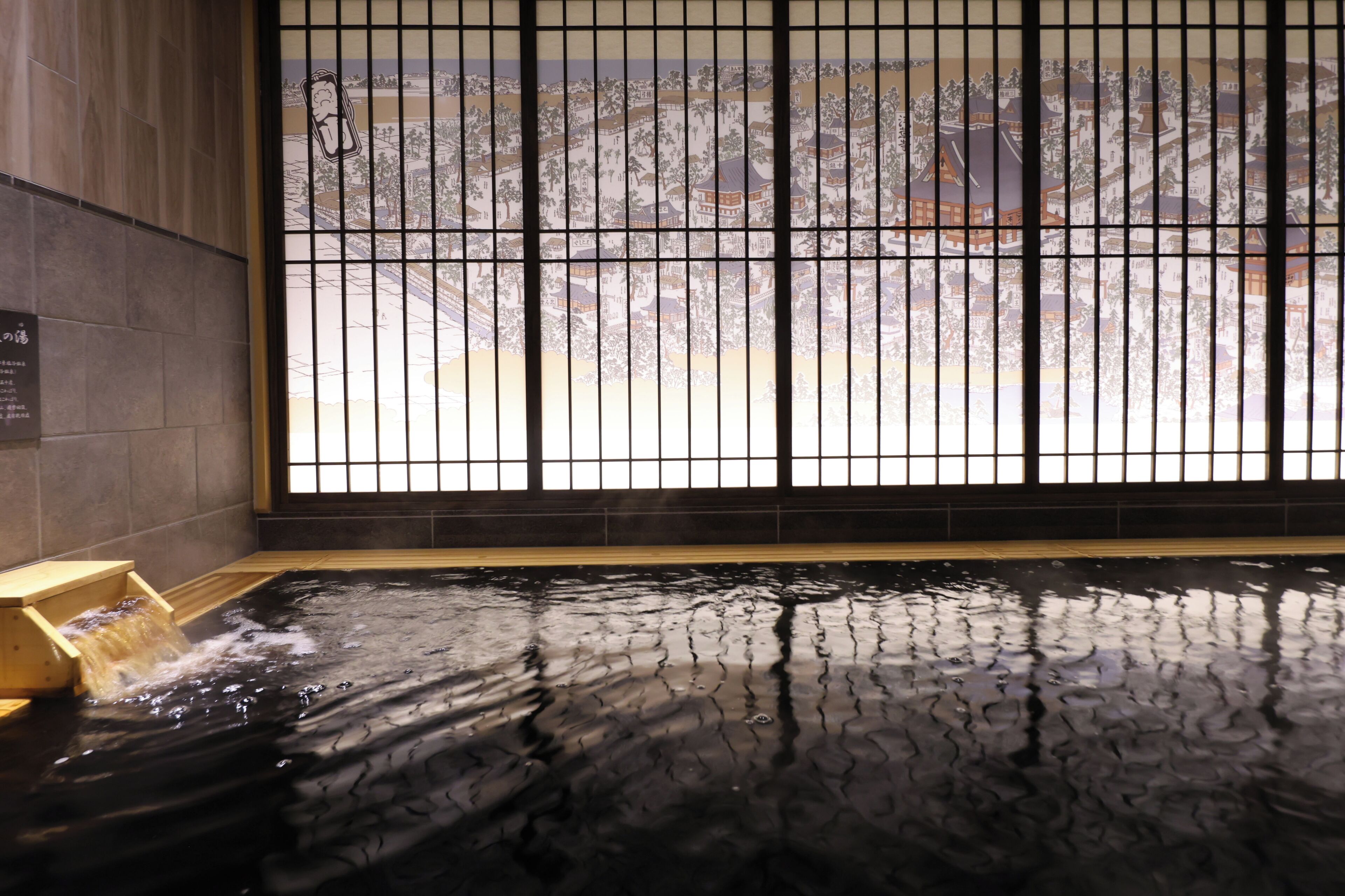 Un onsen japonés tradicional con un banco de madera y vista a un paisaje urbano a través de una ventana con diseño de cuadrícula.