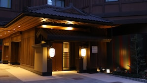Un bâtiment japonais traditionnel, avec une façade en bois, un toit recouvert de tuiles et des lanternes illuminées.