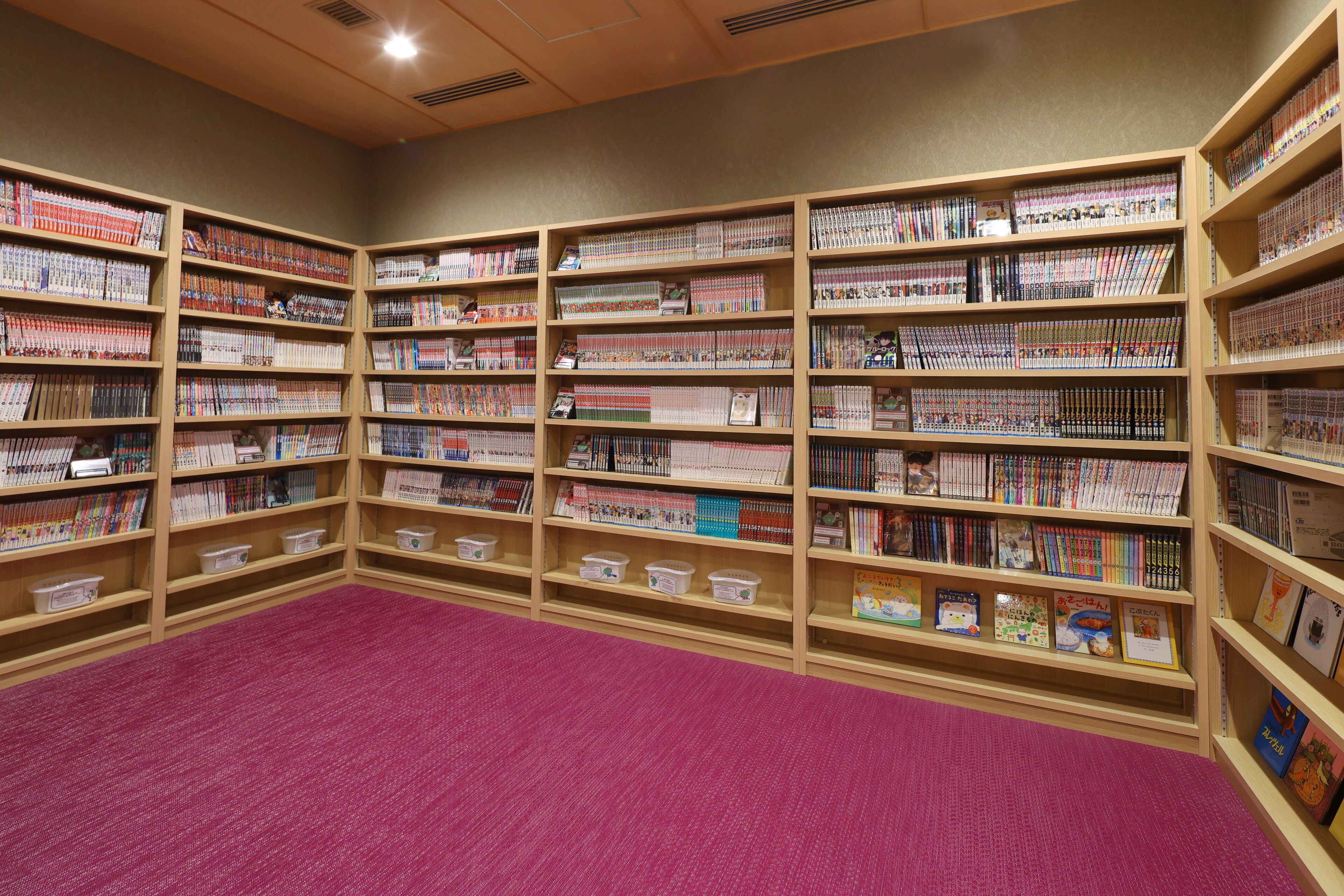 A library with multiple wooden bookshelves filled with books and magazines.