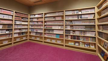 A library with multiple wooden bookshelves filled with books and magazines.