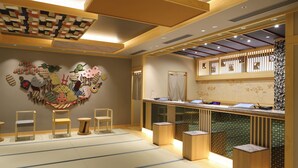 Un espace d’accueil au design japonais traditionnel, comprenant des tatamis, des meubles en bois et un mur décoratif orné de différents motifs.