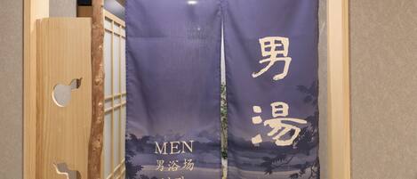 A room with a wooden sliding door and a curtain with Japanese characters and English text.
