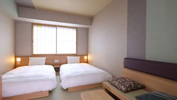 Habitación de hotel con dos camas, una ventana, una mesita de noche y un banco.