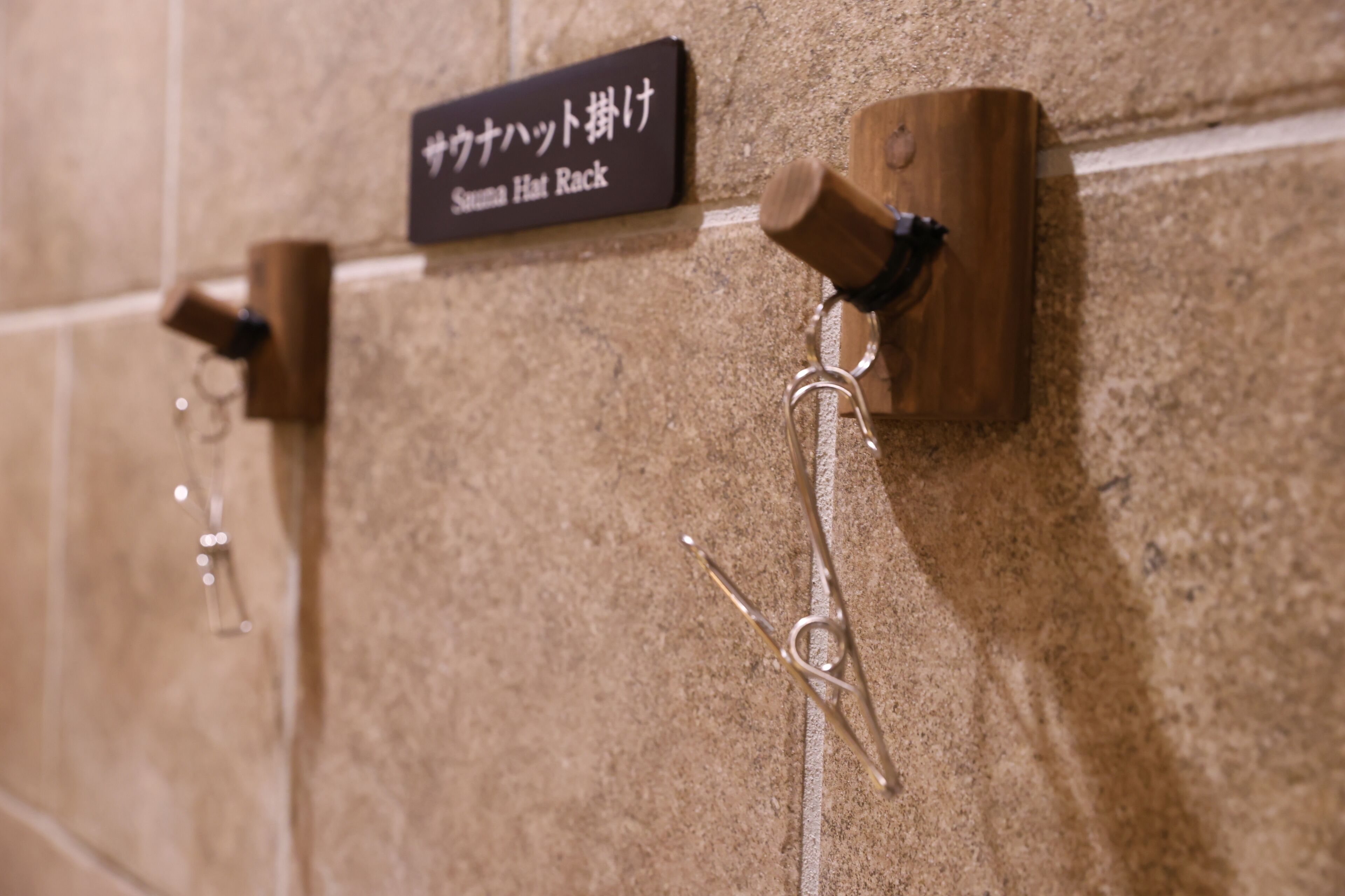 A wall-mounted hat rack with a sign reading "Suma Hat Rack".