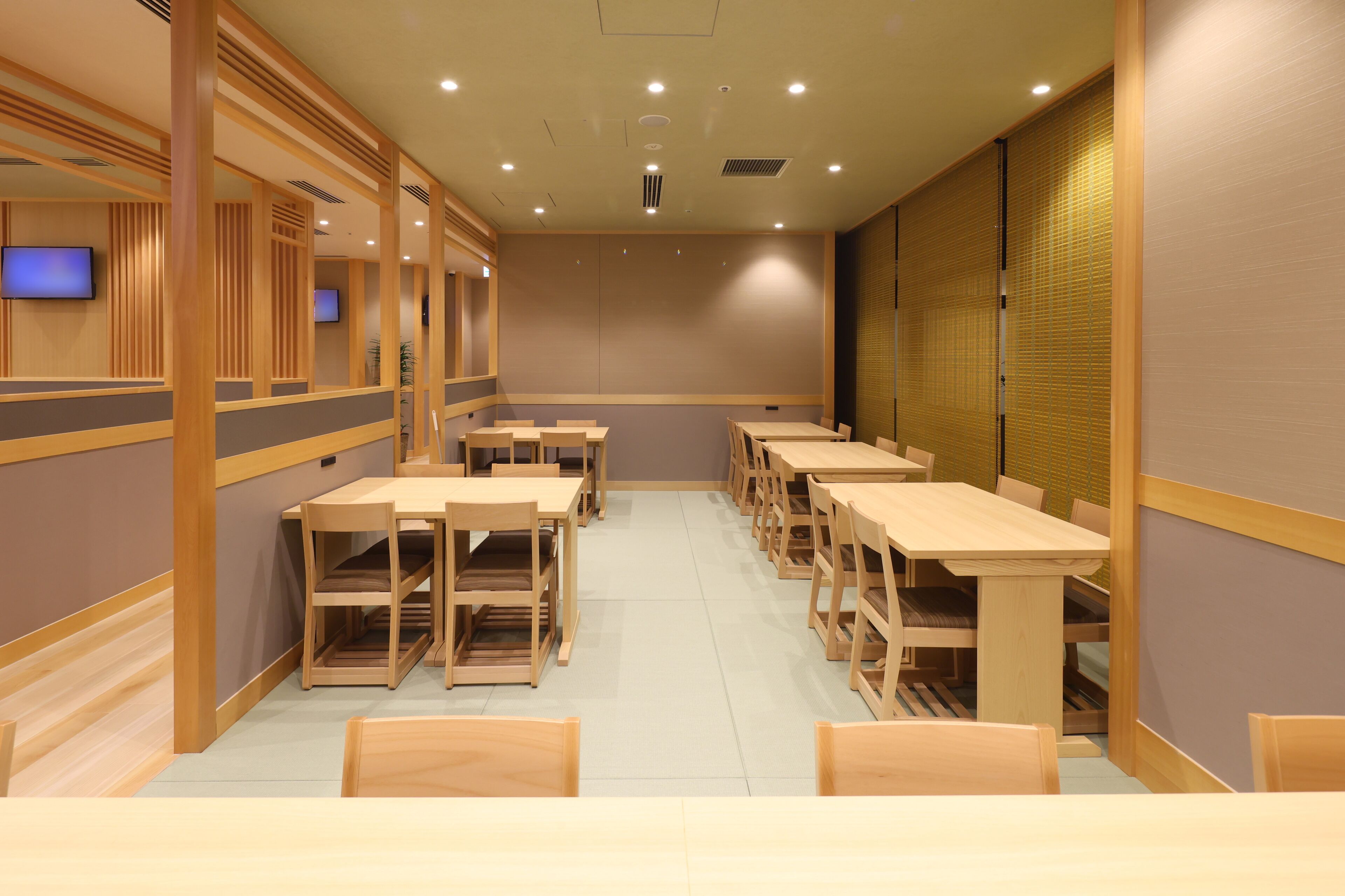 A conference room with multiple tables and chairs, wooden paneling, and recessed ceiling lights.