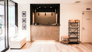 A reception area with a wooden reception desk, a seating bench, a small table, and a bookshelf. - WAYFARER Matsu (Osaka)