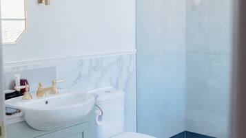 A modern bathroom with a white toilet, a sink, and a shower.