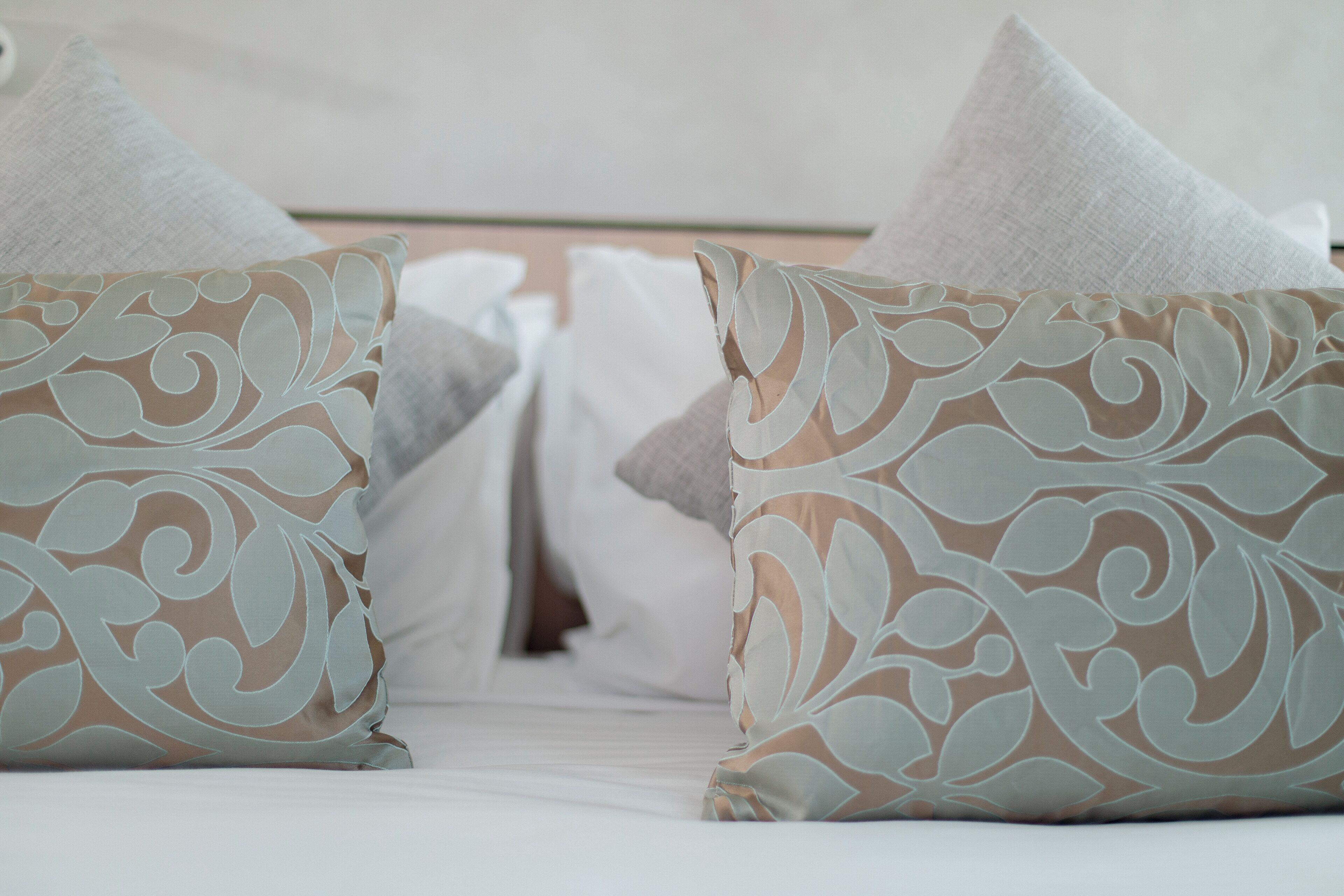 A bed with white bedding and decorative pillows with a floral pattern.