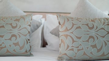 A bed with white bedding and decorative pillows with a floral pattern.
