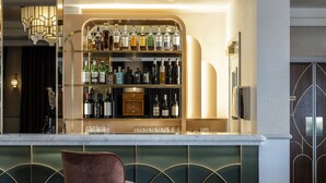 A bar area with a marble countertop, multiple shelves of liquor bottles, and a bar stool.