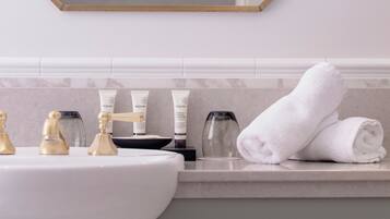A bathroom with a white sink, gold faucets, a large mirror with a gold frame, and a towel on the counter.