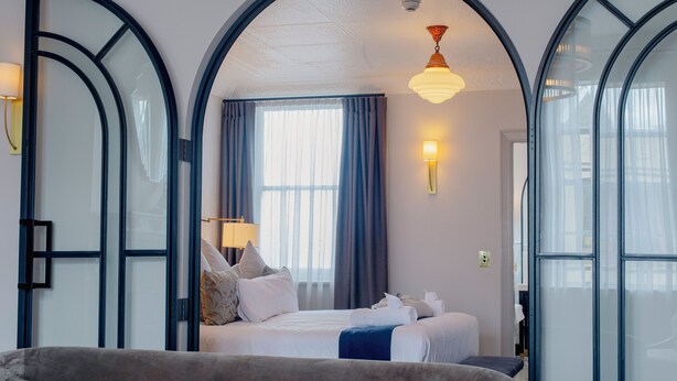 A hotel room with a large bed, a sofa, a desk, and a window with curtains.