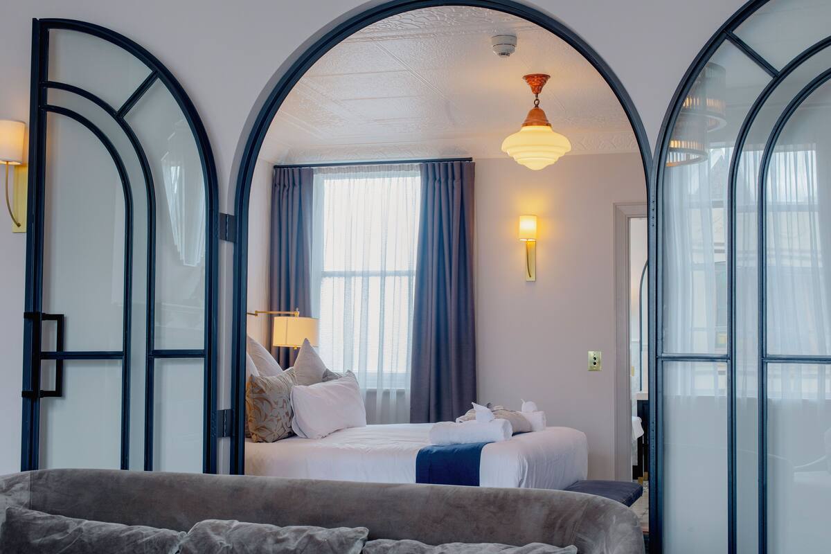 Una habitación de hotel con una cama grande, un sofá, un escritorio y una ventana con cortinas.