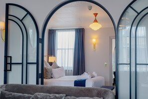 Une chambre d’hôtel avec un grand lit, un canapé, un bureau et une fenêtre avec des rideaux.