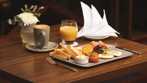 A breakfast setting with a coffee cup, juice, toast, and a plate of eggs and bacon.
