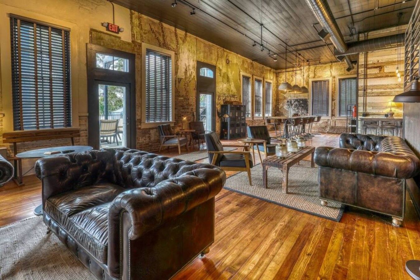 Une pièce spacieuse avec un grand canapé en cuir, un plancher en bois et un mur en briques au style rustique.