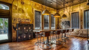 A rustic bar area with wooden flooring, metal bar stools, and pendant lighting.