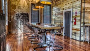 Un intérieur rustique en bois, avec une longue table à manger et des chaises en métal, un extincteur et une porte portant un panneau indiquant la sortie de secours.