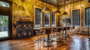 Un coin bar au style rustique, avec un plancher en bois, des tabourets de bar en métal et des lampes suspendues.