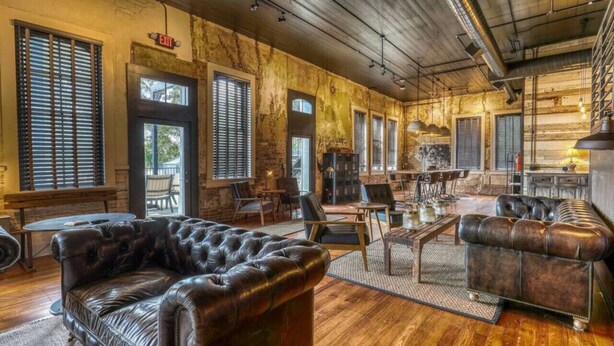 Un intérieur rustique avec des murs en briques apparentes, des canapés en cuir et un plancher en bois.