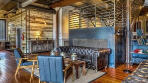 Un salon chaleureux avec un canapé en cuir, une table basse en bois et des fauteuils bleus.